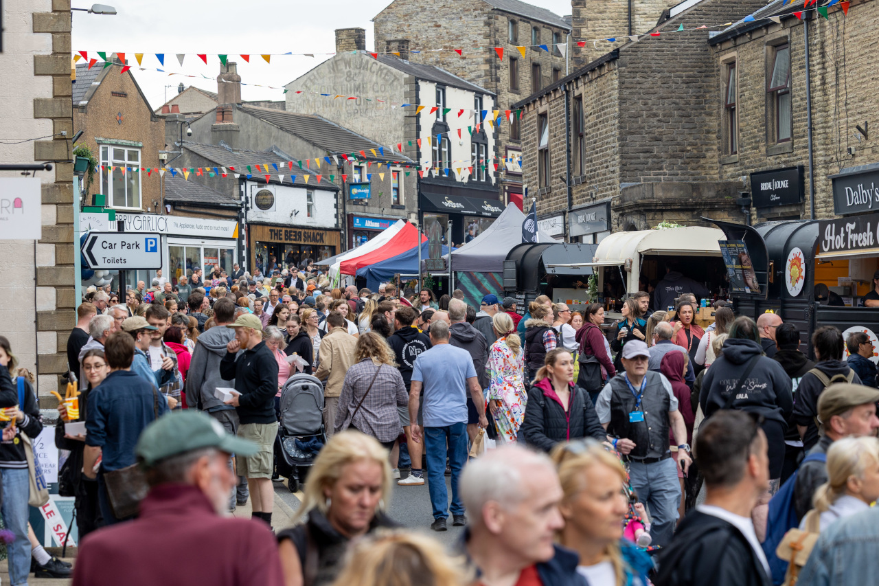 Crowds at the Clitheroe Food Festival. Marquees selling food are set up along the pavement.