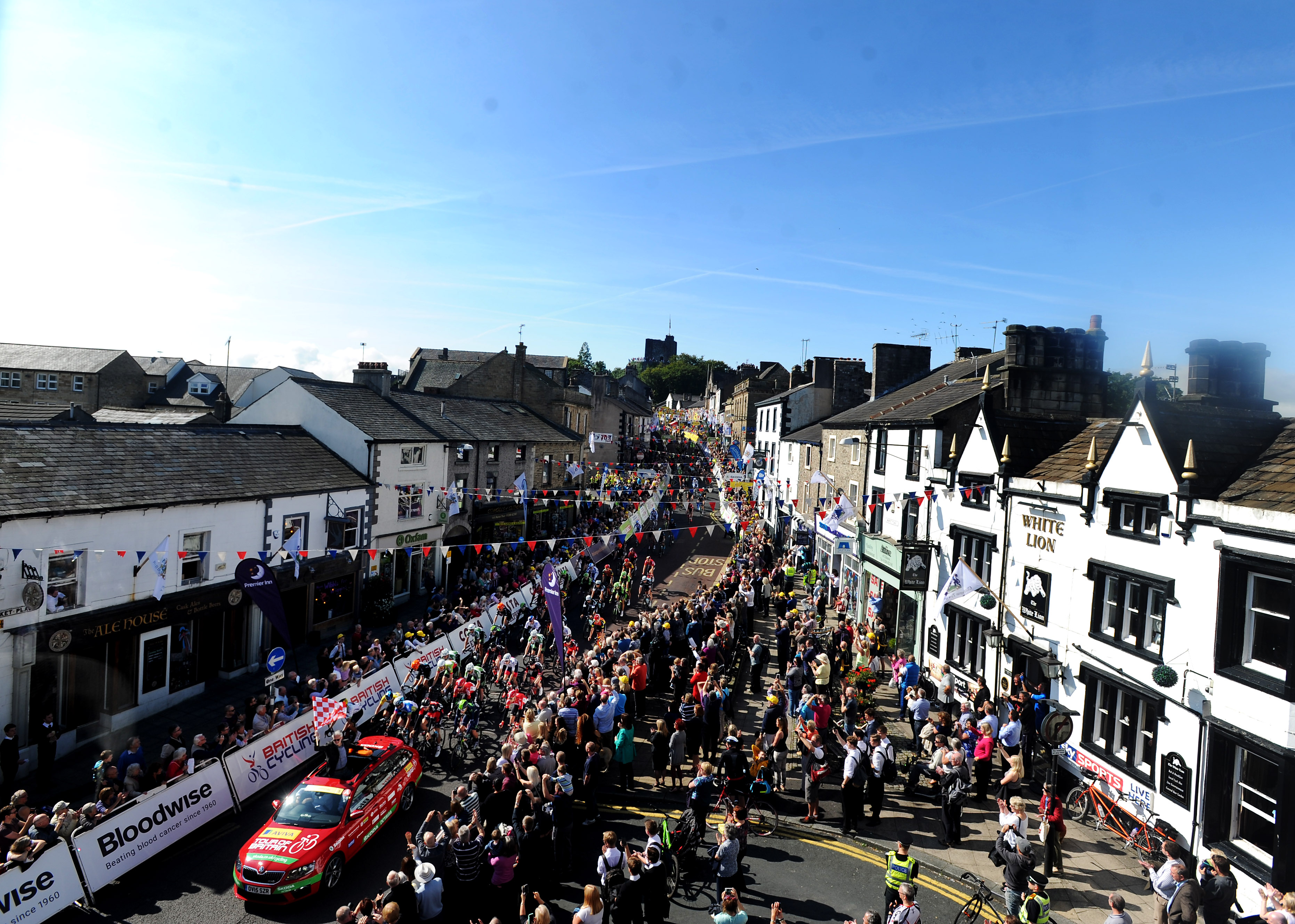 An aerial photo of the start of the Tour of Britain Mens cycle race in 2015. There are cyclist heading down through the centre of Clitheroe and large crowds on both sides of the road.