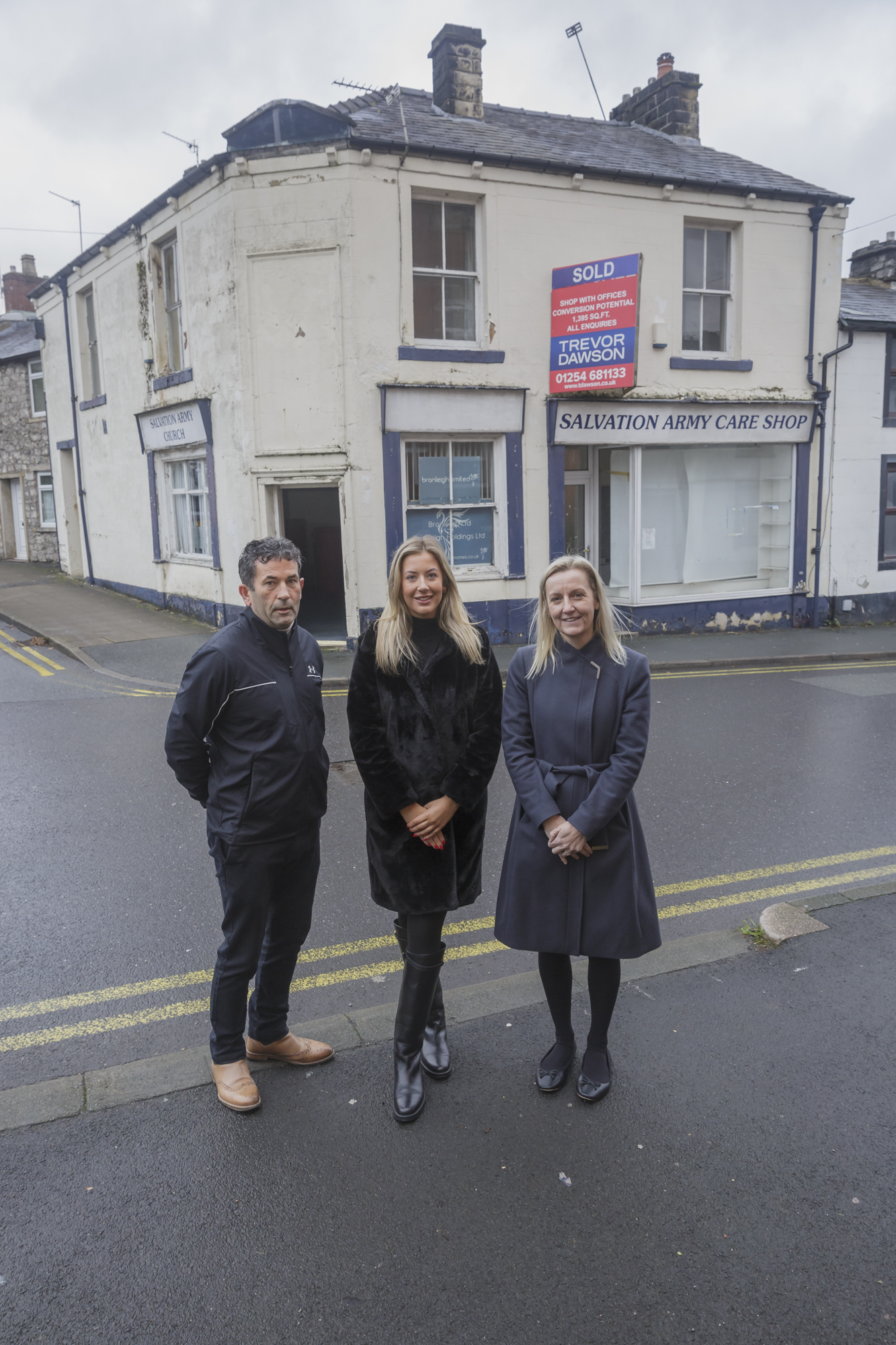 Three people stood outside a white corner building formerly home to the Salvation Army in Clitheroe.