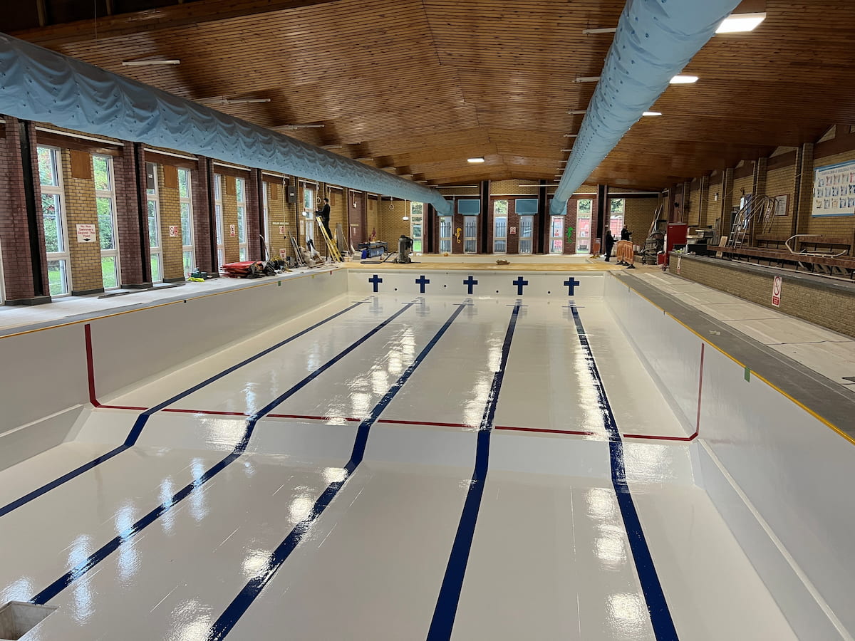 Ribblesdale Pool empty of water whilst a workman works in the background.